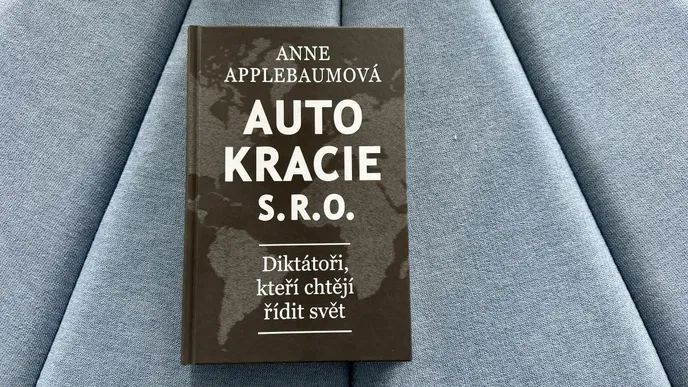 Kniha Autokracie, s. r. o. položená na modré sedačce